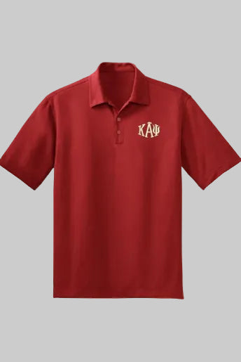 A man wearing a red short-sleeved polo shirt with the Kappa Alpha Psi fraternity logo on the chest, paired with beige pants and a brown belt.